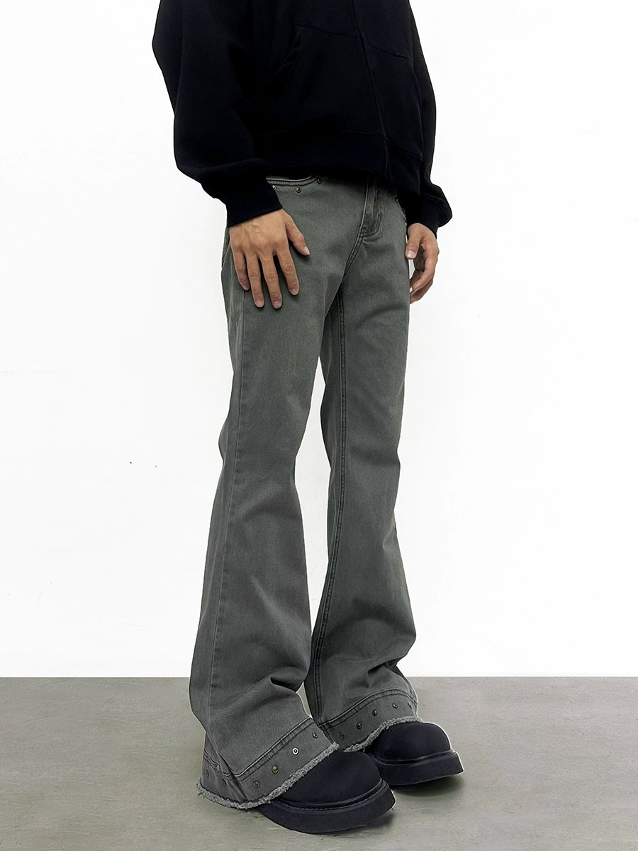 Person wearing gray flared pants and black shoes on a white background