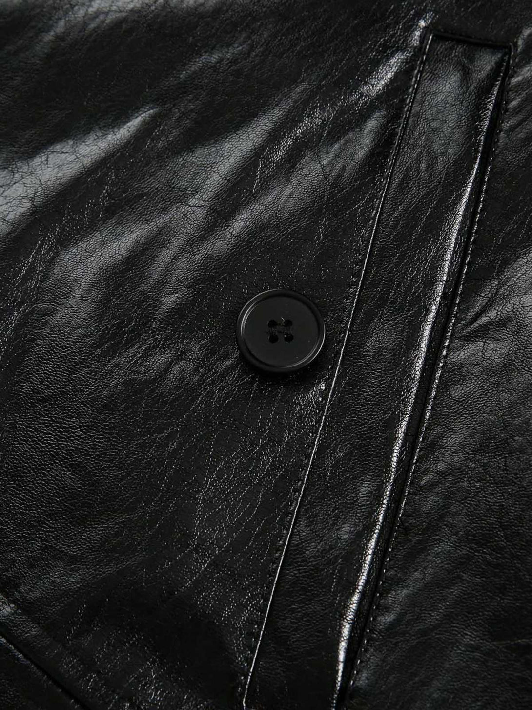 Close-up of a black leather jacket with a button