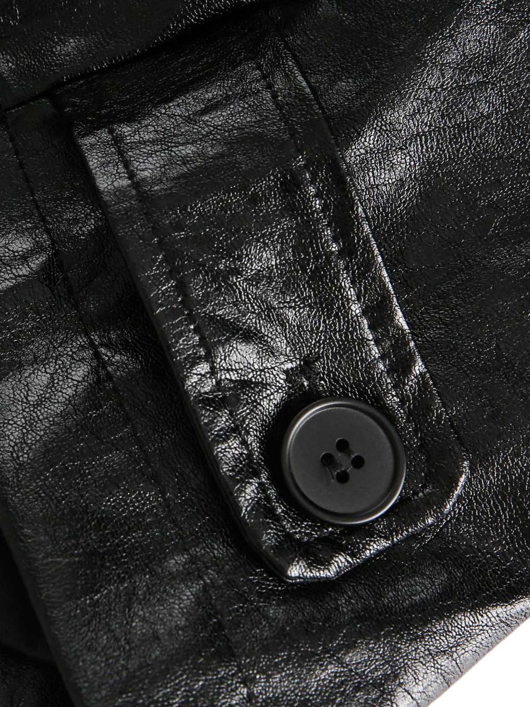 Close-up of a black leather button on a textured surface