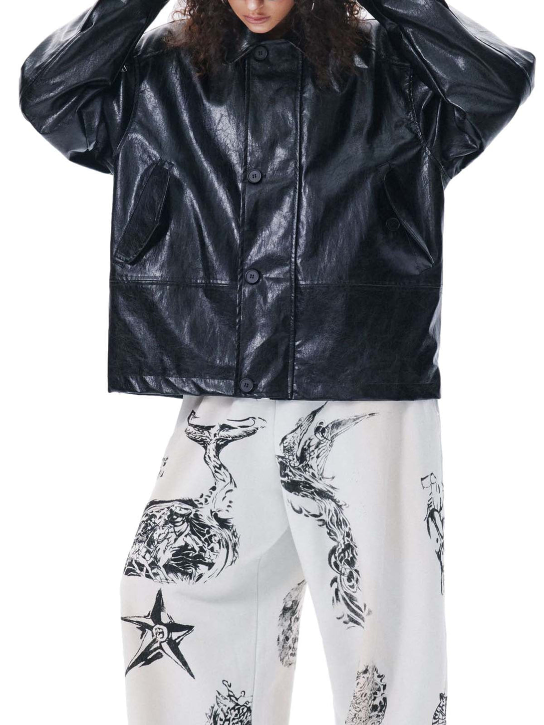 Person wearing a black leather jacket and white pants with black patterns on a white background