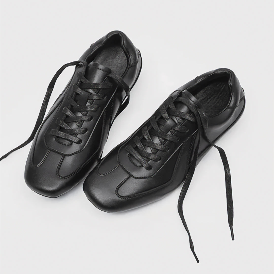 Pair of black leather sneakers on a light gray background