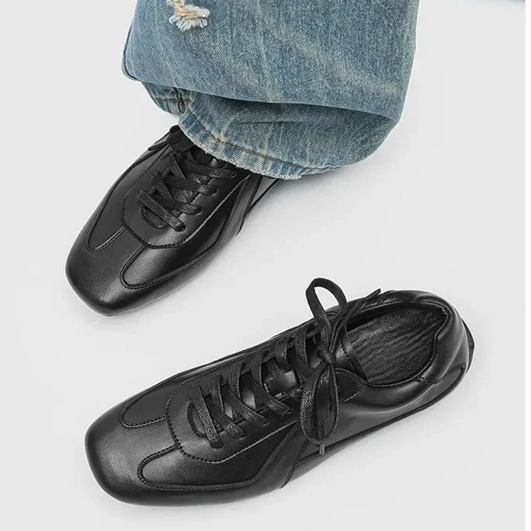 Black sneakers worn with blue jeans on a light gray background