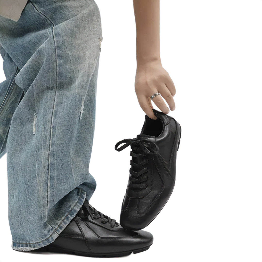 Person wearing black shoes with blue jeans on a white background