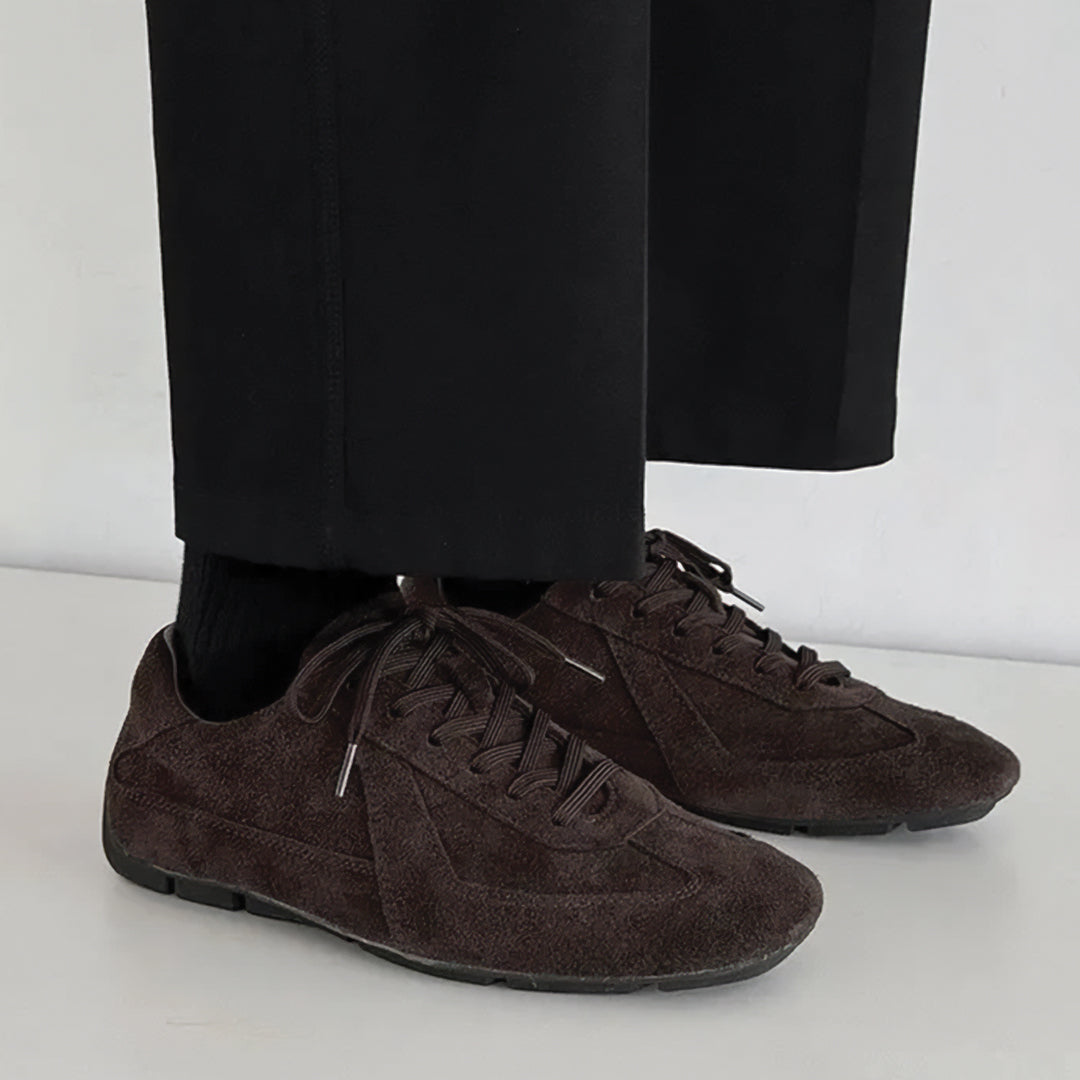 Brown suede shoes worn with black pants on a white background