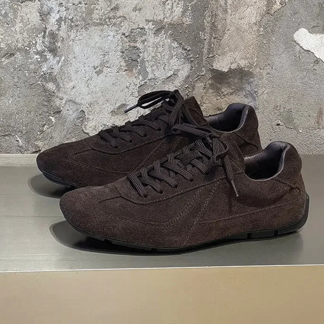 Pair of brown sneakers on a metallic surface with a textured gray wall background