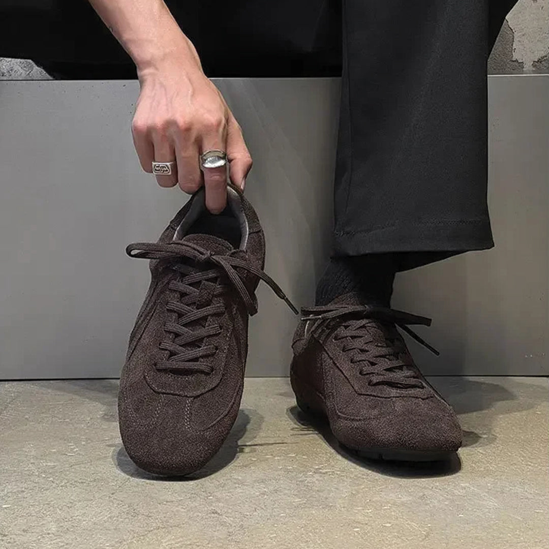 Person wearing brown suede shoes with a neutral background