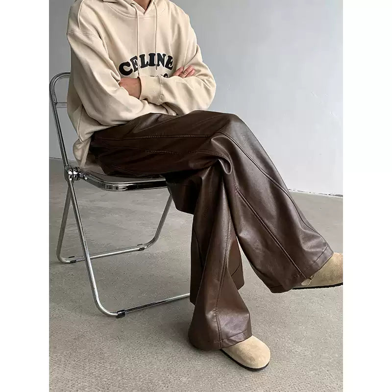 Person wearing a beige hoodie and brown leather pants sitting on a chair.