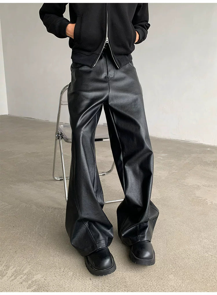 Person wearing black leather pants and shoes in a minimal indoor setting