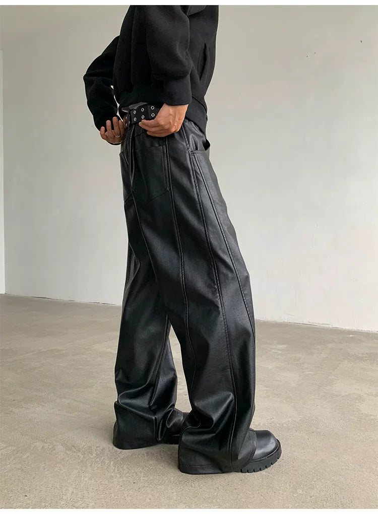 Person wearing black pants and a black jacket standing against a plain background