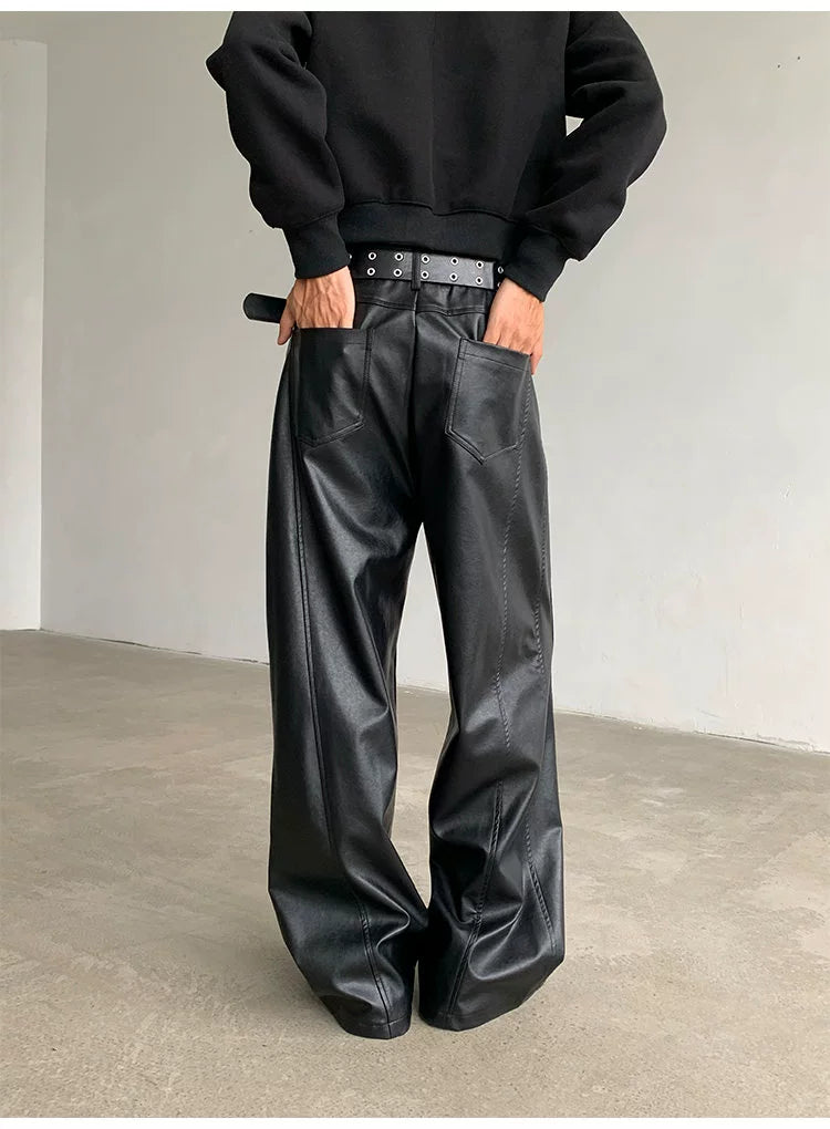 Person wearing black leather pants and a black sweatshirt against a plain background