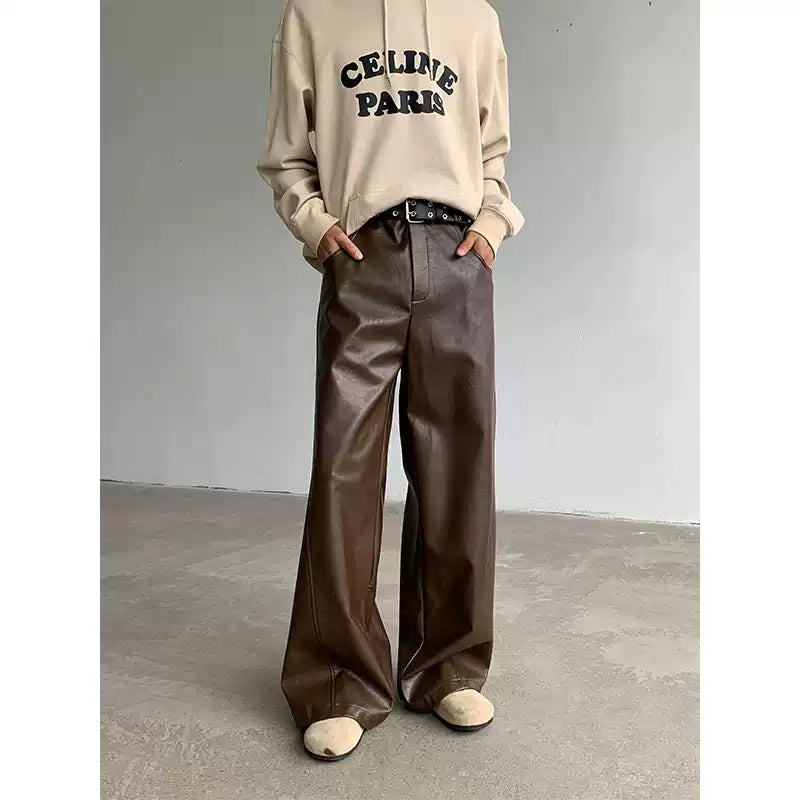 Person wearing a beige 'CELINE PARIS' hoodie and brown leather pants on a plain background